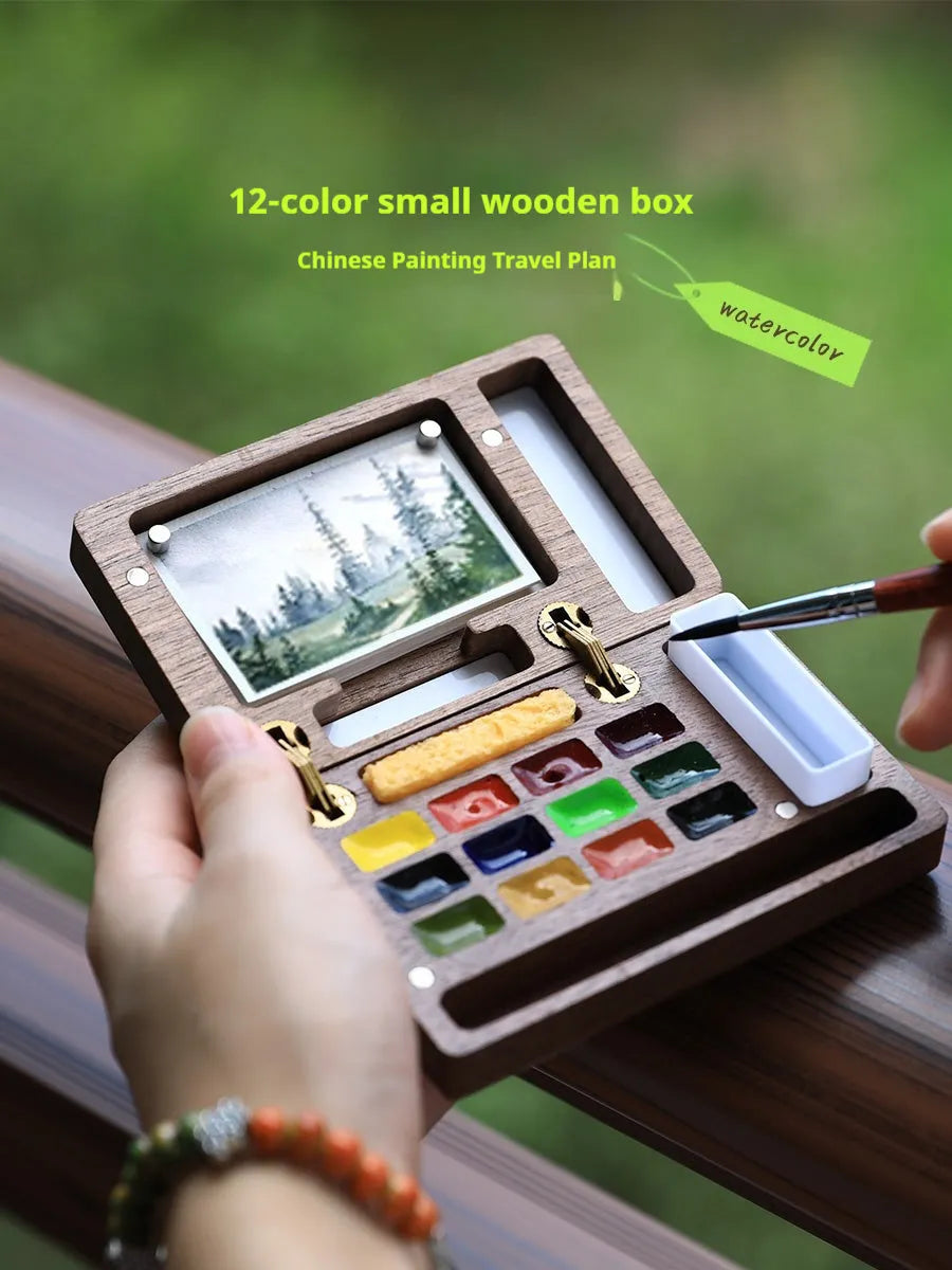 Miniature walnut wood watercolour paint box open to show pigment pans and wooden palette