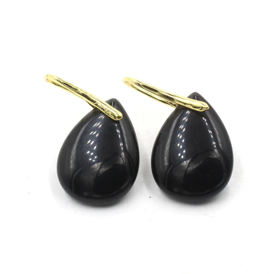 A pair of geometric water drop earrings made from crystal, shown in one of nine available colours like amethyst or obsidian.