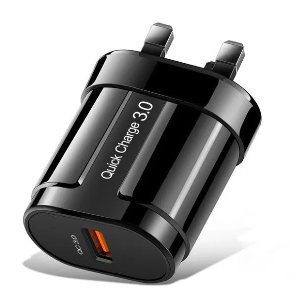 White and black mobile phone travel chargers with UK, US, and EU plug attachments on a table