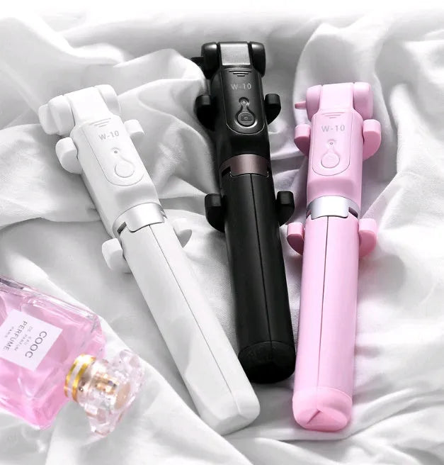 Aluminium Bluetooth selfie stick with tripod base and remote control next to a smartphone.