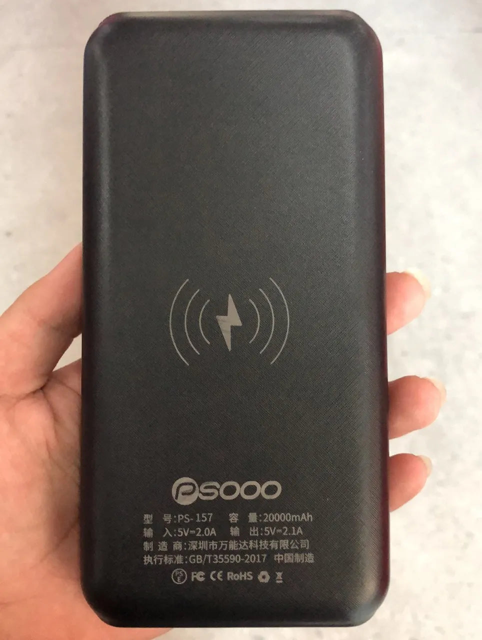Portable power bank with wireless charging pad and three USB ports in black plastic casing