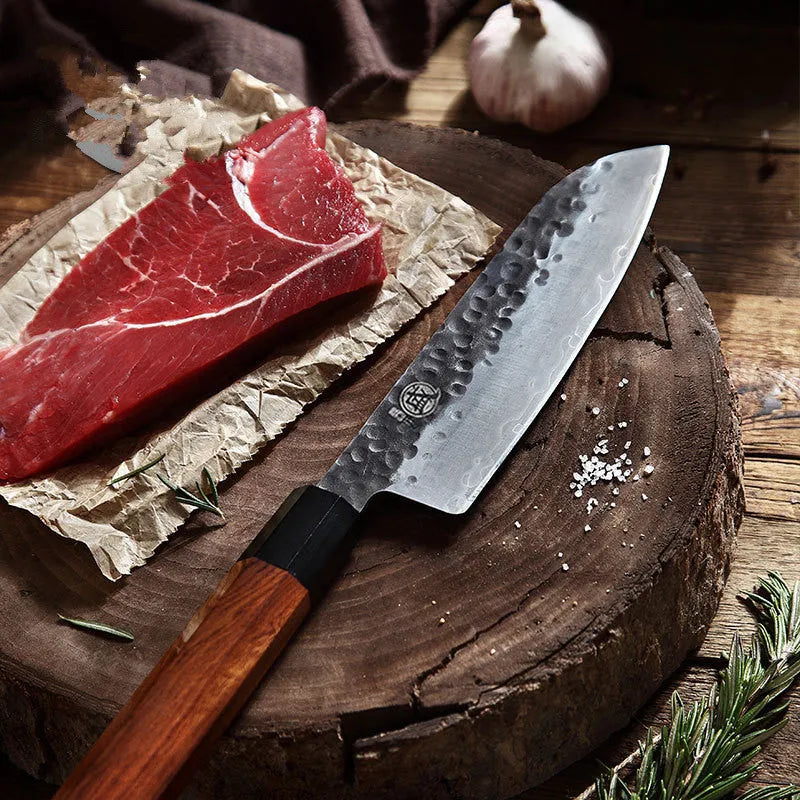 Hand forged Santoku chef knife with 149 cm silver blade on cutting board