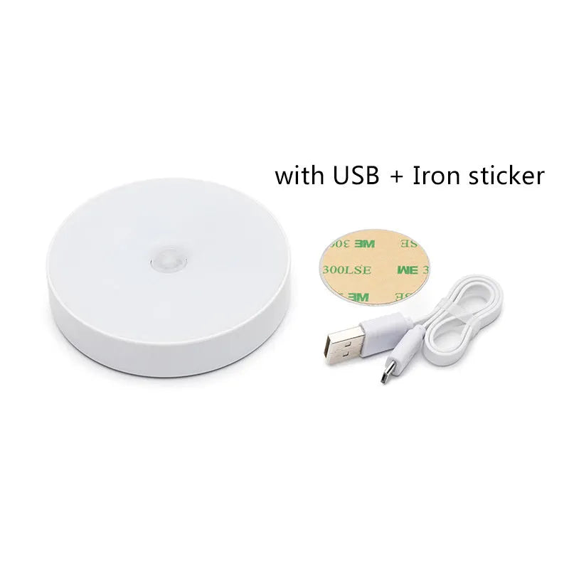Small white circular motion sensing LED night light with adhesive backing next to a USB charging cable.
