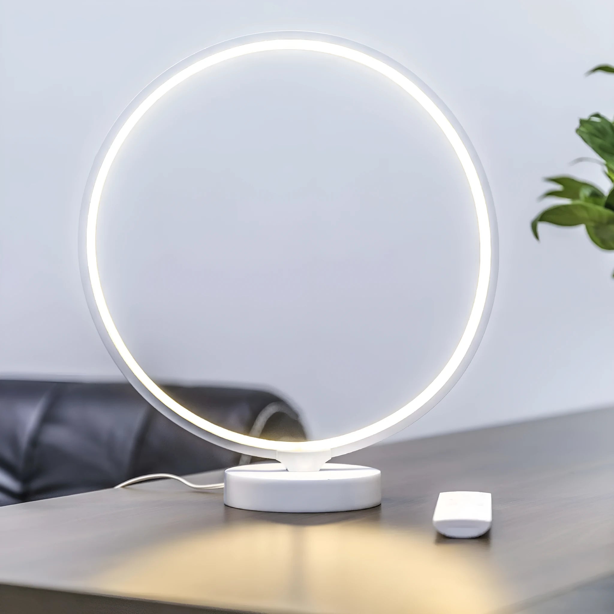 White Full Moon table lamp with remote control on a wooden surface.