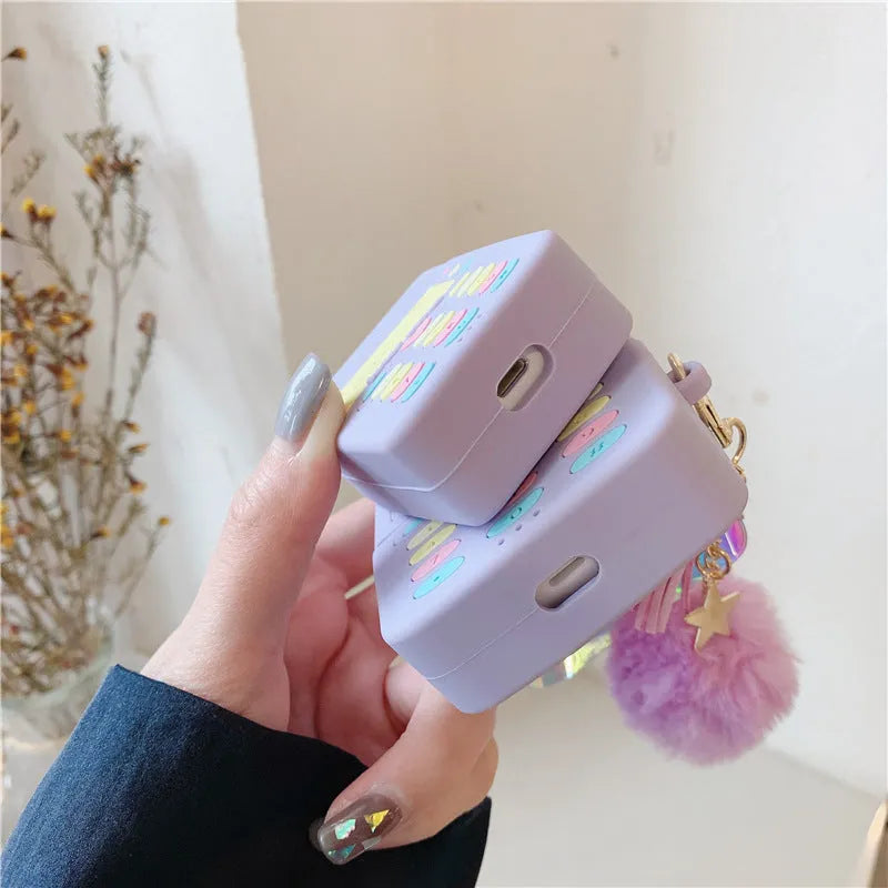 Purple silicone clamshell case for AirPods Pro or AirPods 1 and 2 with a matching fur ball pendant attached.