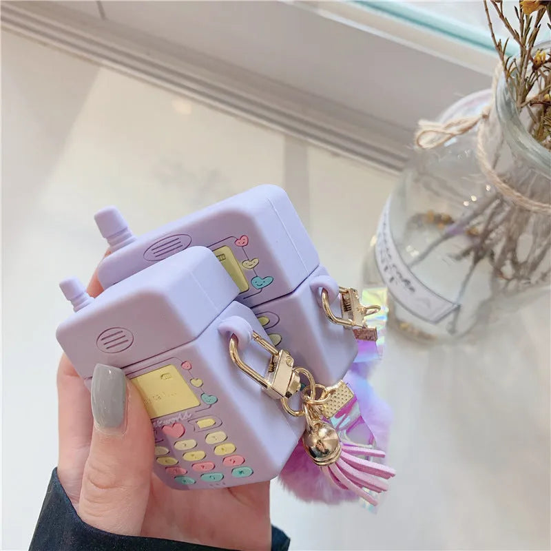 Purple silicone clamshell case for AirPods Pro or AirPods 1 and 2 with a matching fur ball pendant attached.