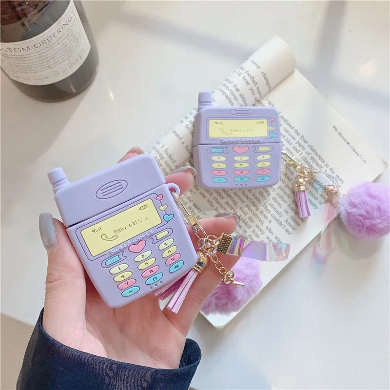 Purple silicone clamshell case for AirPods Pro or AirPods 1 and 2 with a matching fur ball pendant attached.