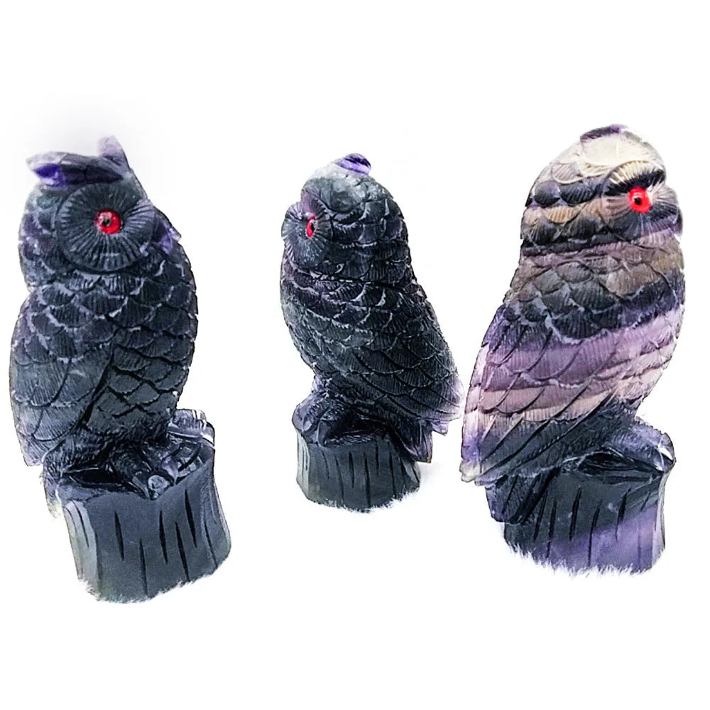Hand-carved purple fluorite owl ornament on a neutral background, showing natural stone colour and texture.