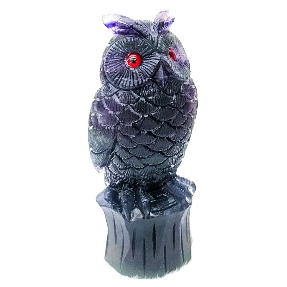 Hand-carved purple fluorite owl ornament on a neutral background, showing natural stone colour and texture.