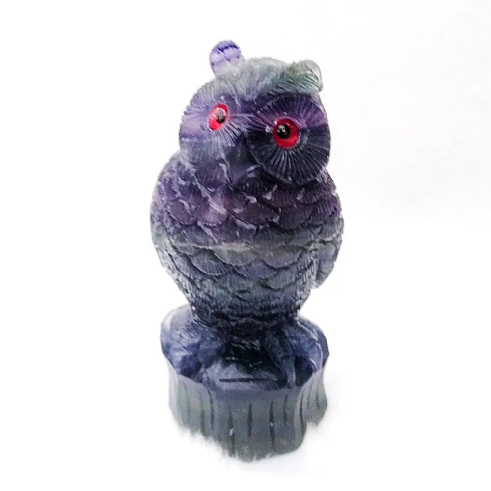 Hand-carved purple fluorite owl ornament on a neutral background, showing natural stone colour and texture.