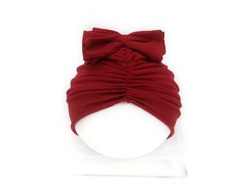 Soft acrylic knitted baby hat in a solid colour, shown on a mannequin as a turban-style cap for infants 0-28 months.