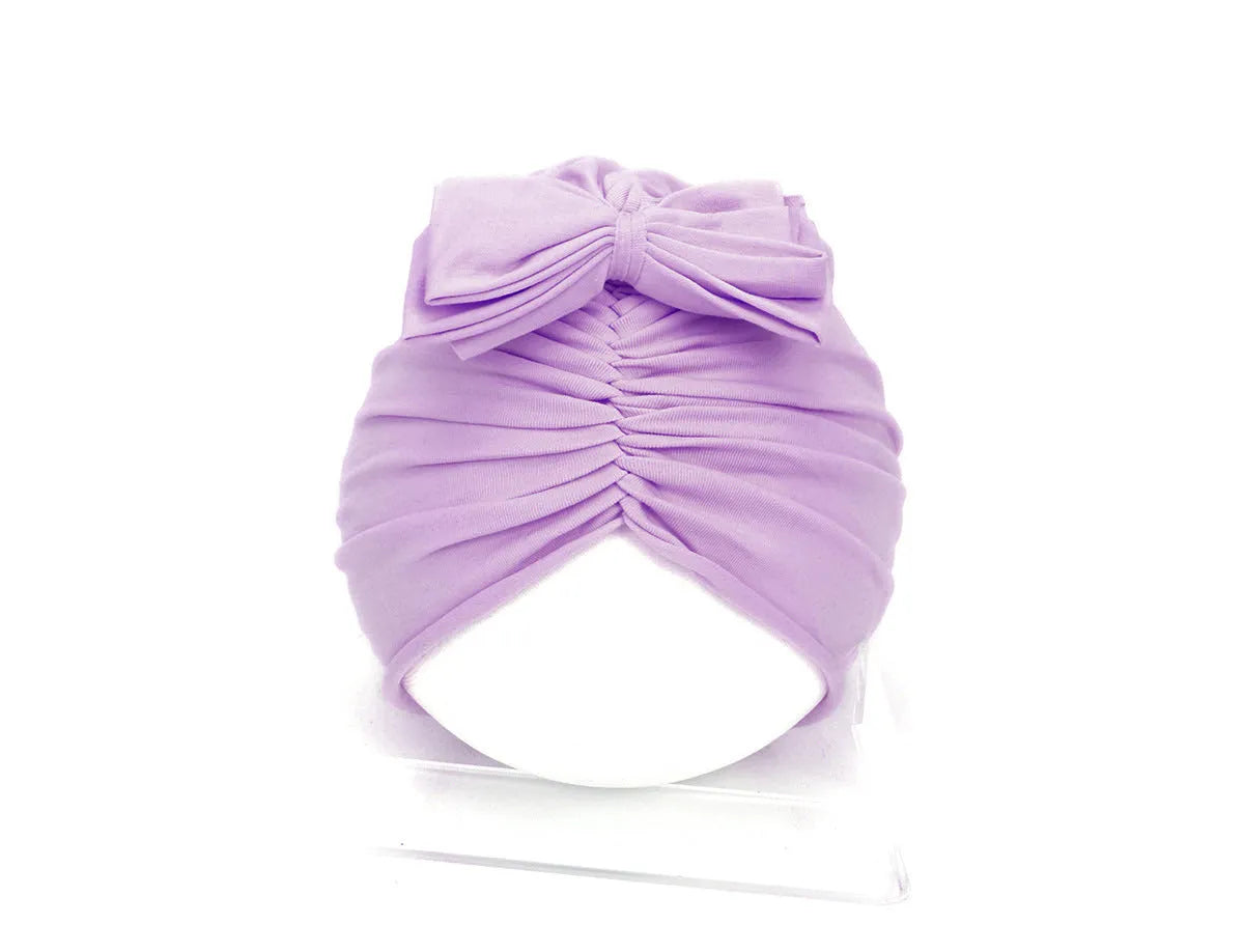 Soft acrylic knitted baby hat in a solid colour, shown on a mannequin as a turban-style cap for infants 0-28 months.