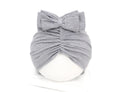 Soft acrylic knitted baby hat in a solid colour, shown on a mannequin as a turban-style cap for infants 0-28 months.