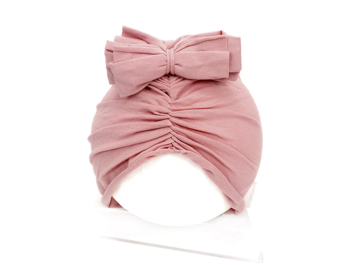 Soft acrylic knitted baby hat in a solid colour, shown on a mannequin as a turban-style cap for infants 0-28 months.