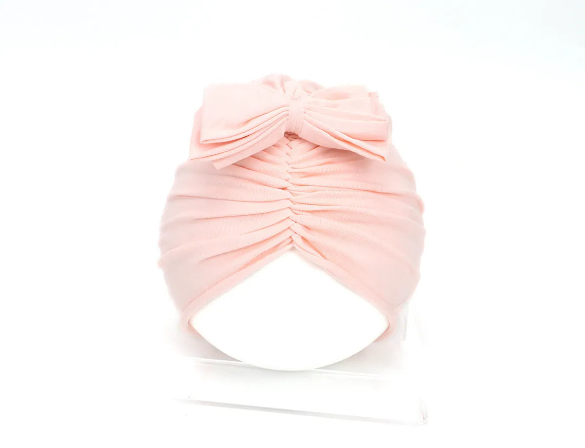 Soft acrylic knitted baby hat in a solid colour, shown on a mannequin as a turban-style cap for infants 0-28 months.