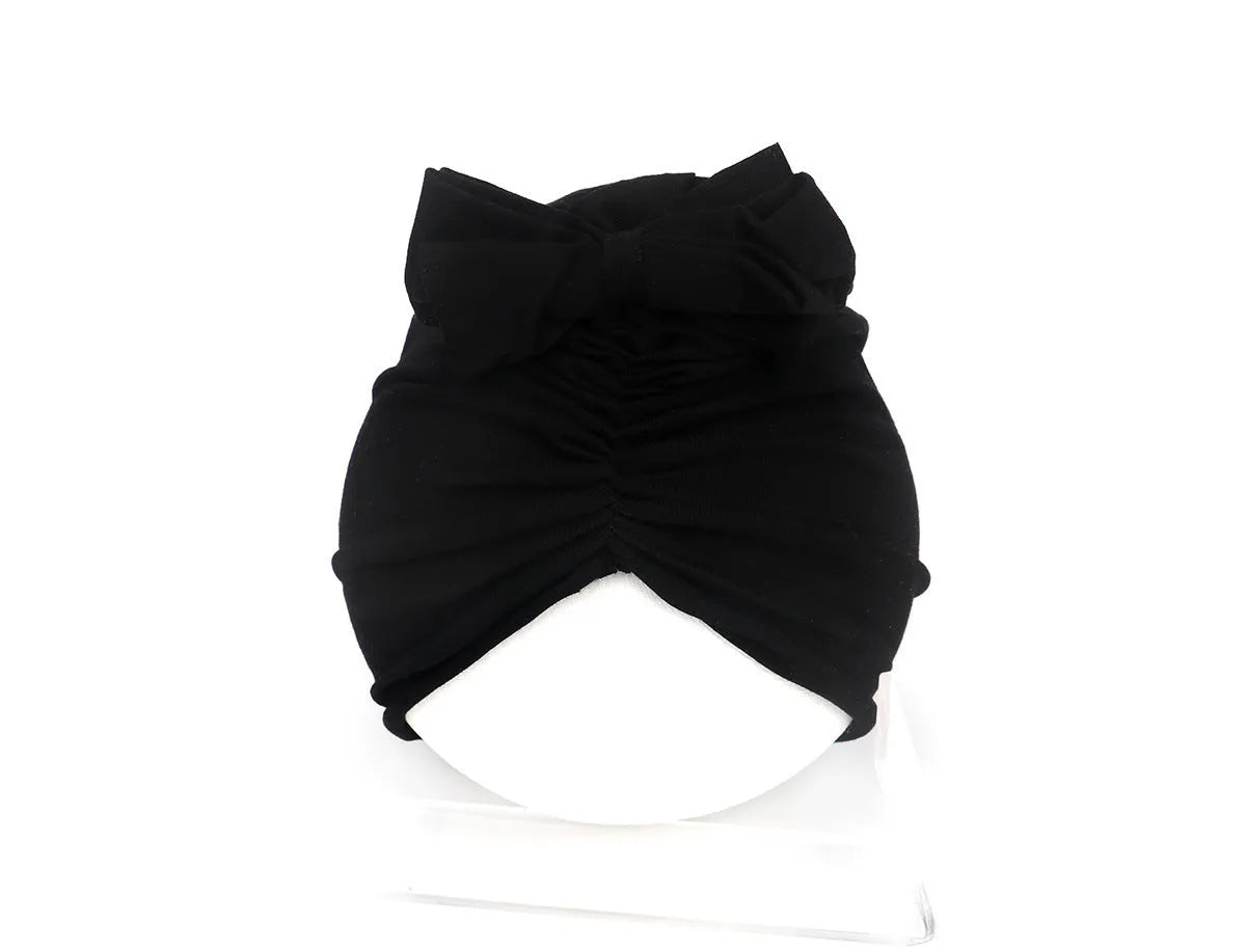 Soft acrylic knitted baby hat in a solid colour, shown on a mannequin as a turban-style cap for infants 0-28 months.