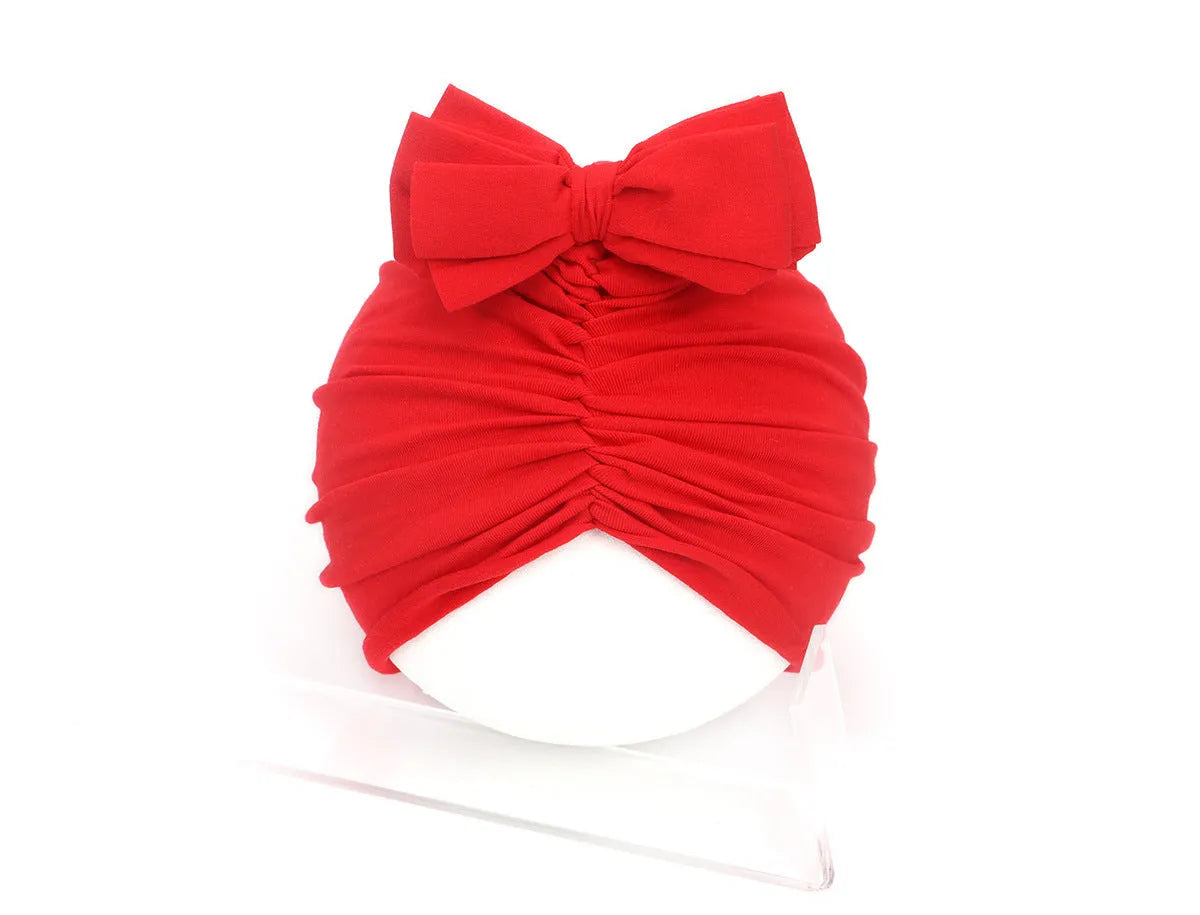 Soft acrylic knitted baby hat in a solid colour, shown on a mannequin as a turban-style cap for infants 0-28 months.