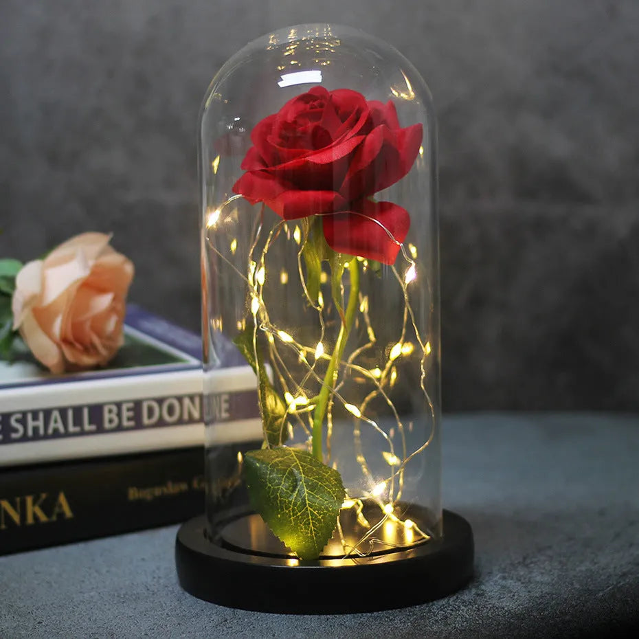 Simulated pink silk rose inside a glass dome with glowing LED fairy lights