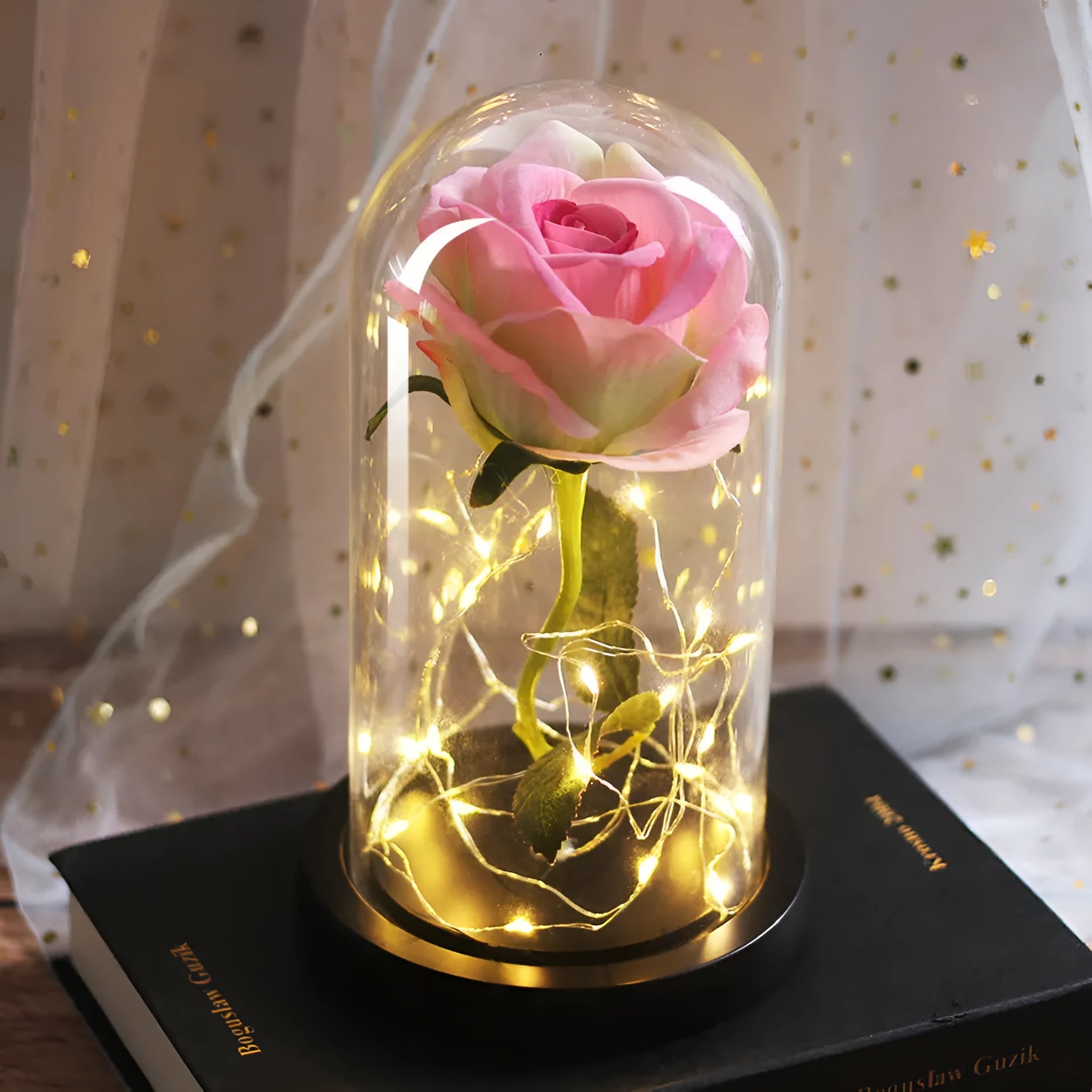 Simulated pink silk rose inside a glass dome with glowing LED fairy lights
