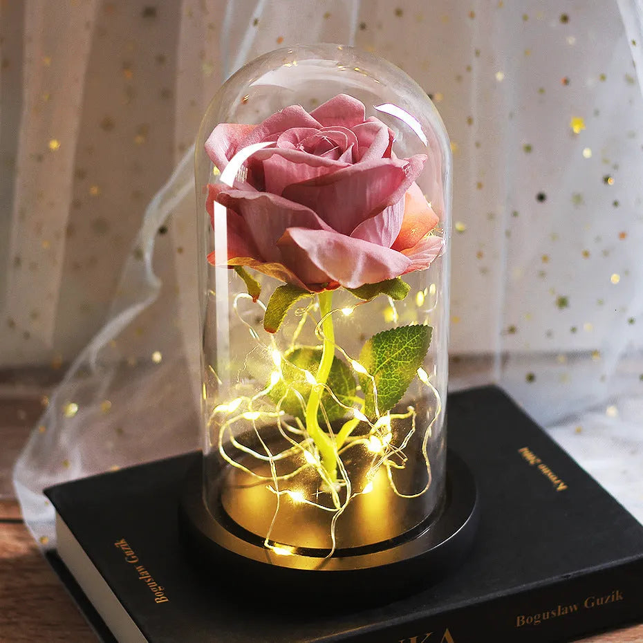 Simulated pink silk rose inside a glass dome with glowing LED fairy lights