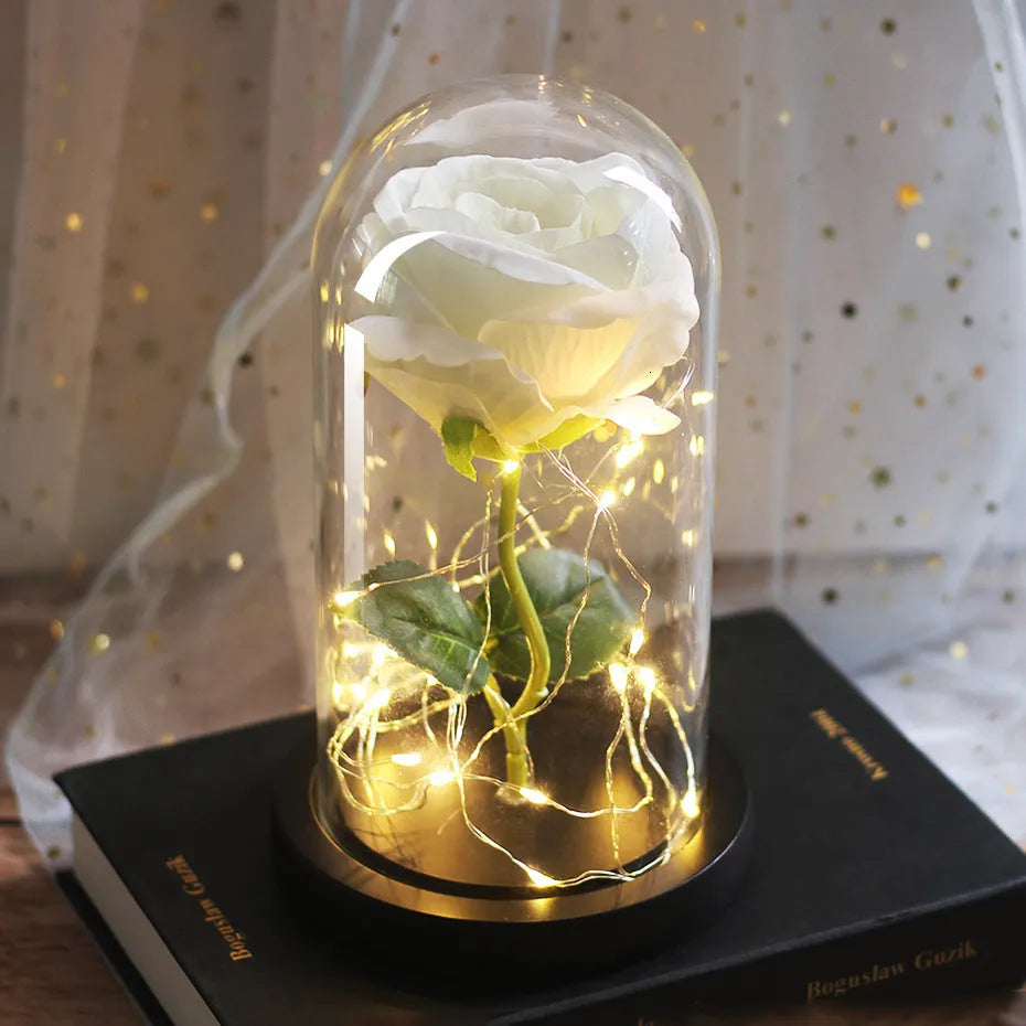 Simulated pink silk rose inside a glass dome with glowing LED fairy lights
