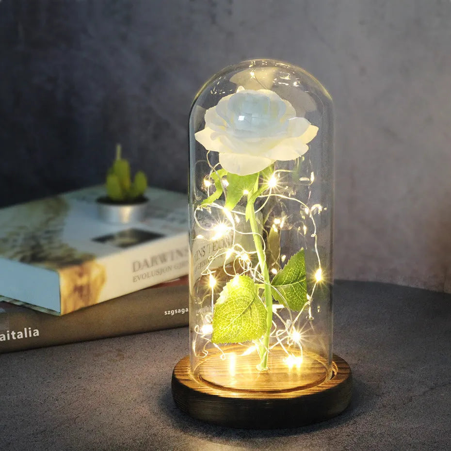 Simulated pink silk rose inside a glass dome with glowing LED fairy lights