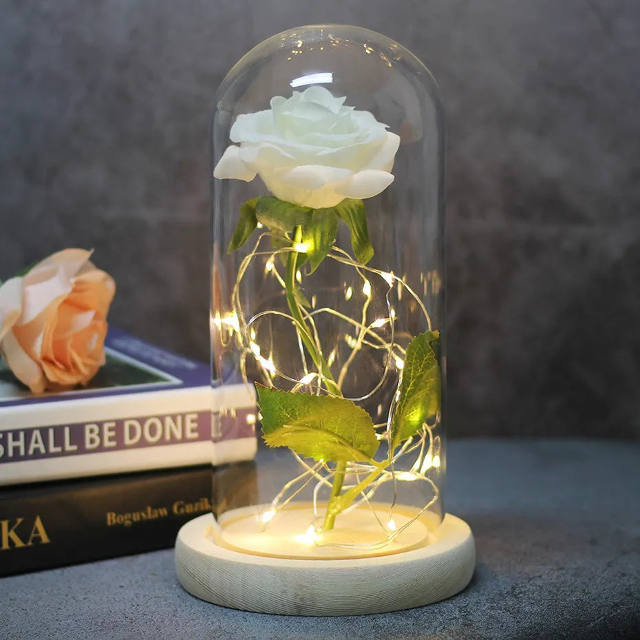 Simulated pink silk rose inside a glass dome with glowing LED fairy lights