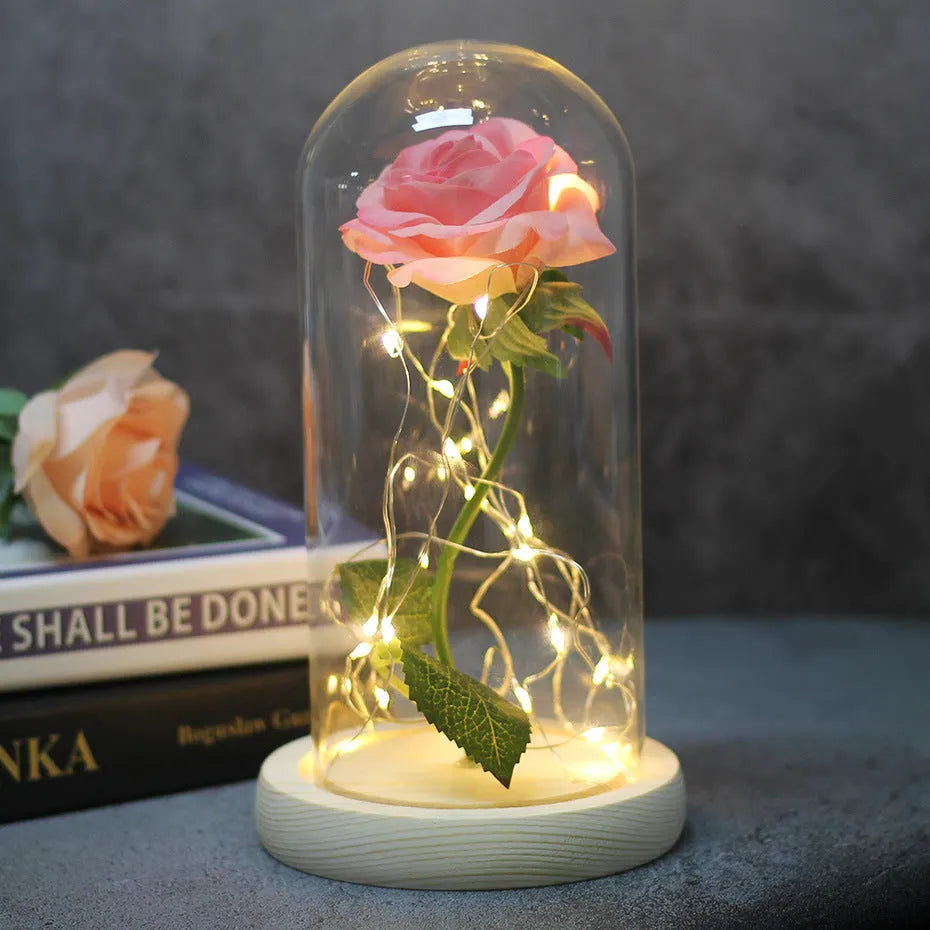 Simulated pink silk rose inside a glass dome with glowing LED fairy lights