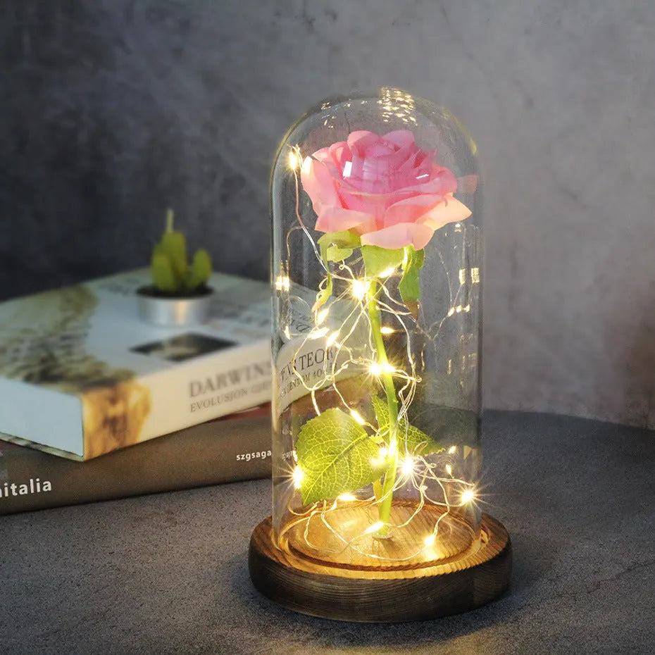 Simulated pink silk rose inside a glass dome with glowing LED fairy lights