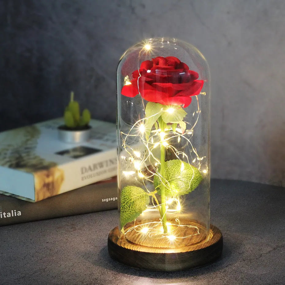 Simulated pink silk rose inside a glass dome with glowing LED fairy lights