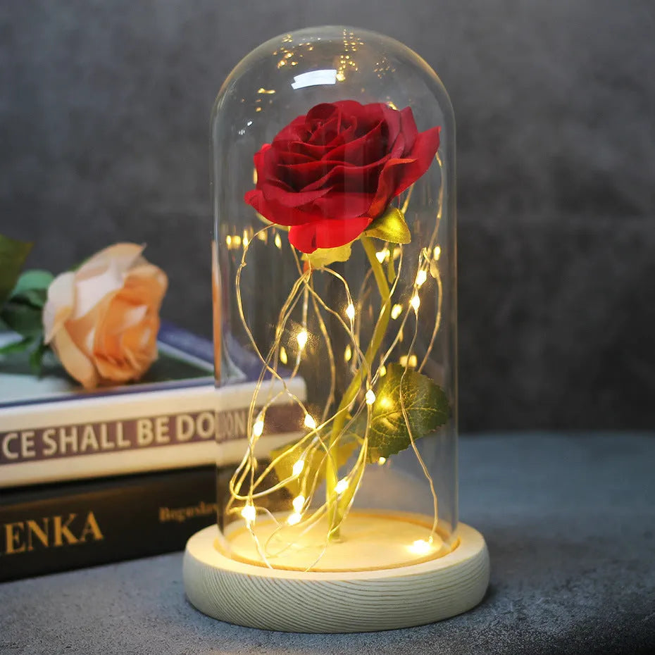 Simulated pink silk rose inside a glass dome with glowing LED fairy lights