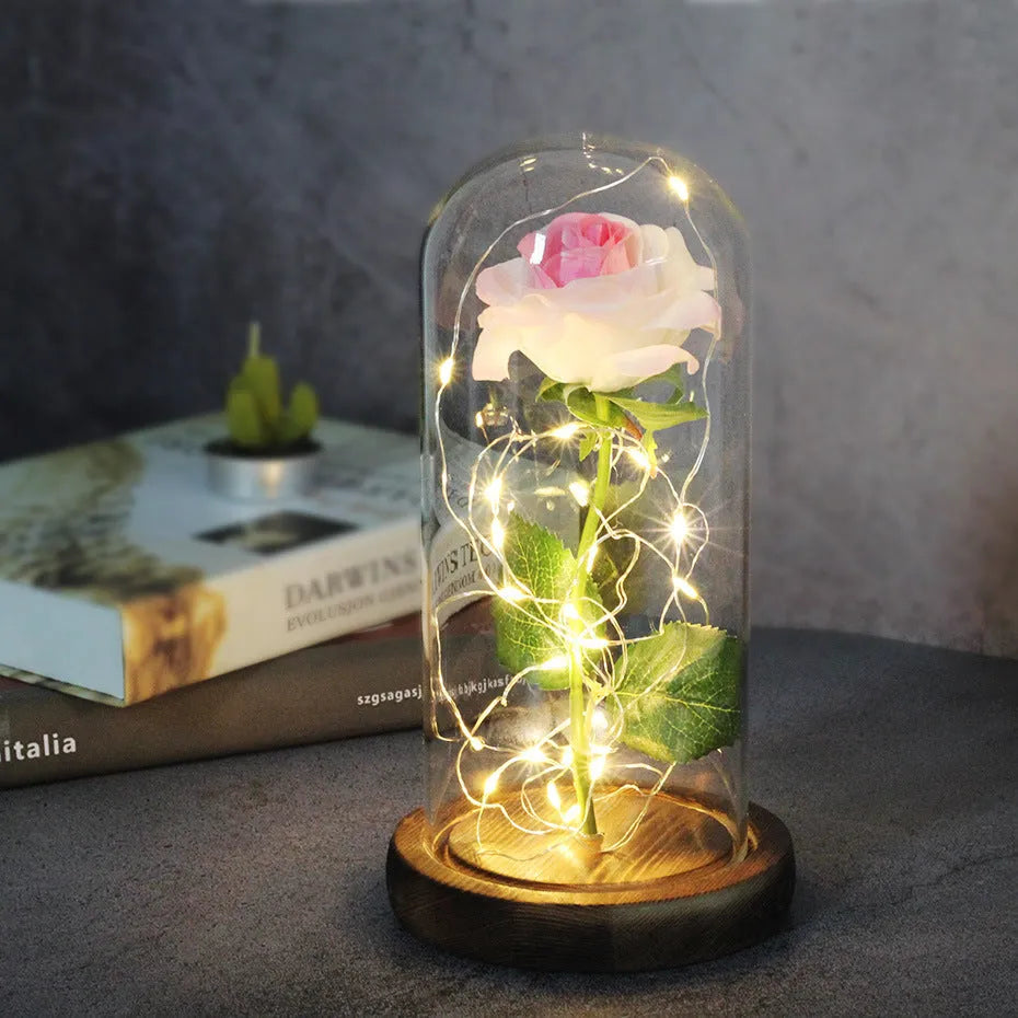 Simulated pink silk rose inside a glass dome with glowing LED fairy lights
