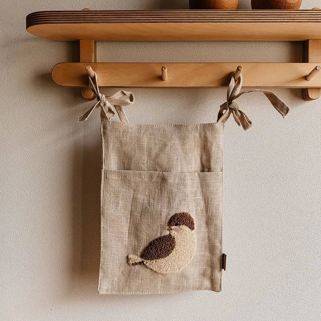 Khaki cotton and linen multi-purpose storage bag hanging beside the bed with single pocket