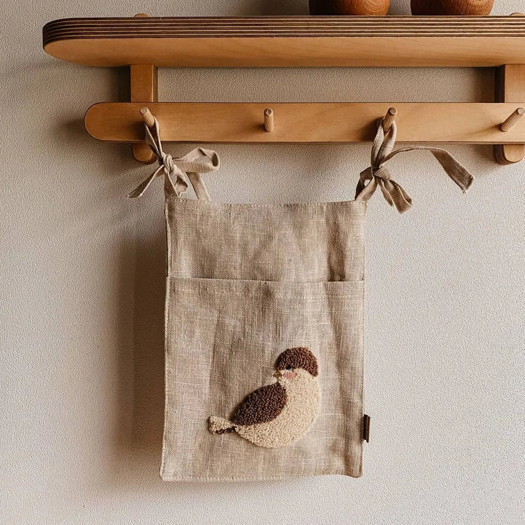 Khaki cotton and linen multi-purpose storage bag hanging beside the bed with single pocket