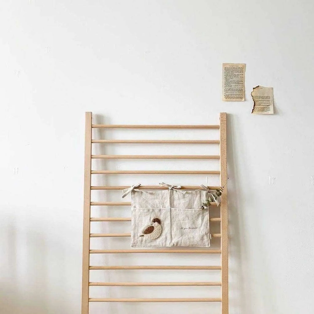 Khaki cotton and linen multi-purpose storage bag hanging beside the bed with single pocket