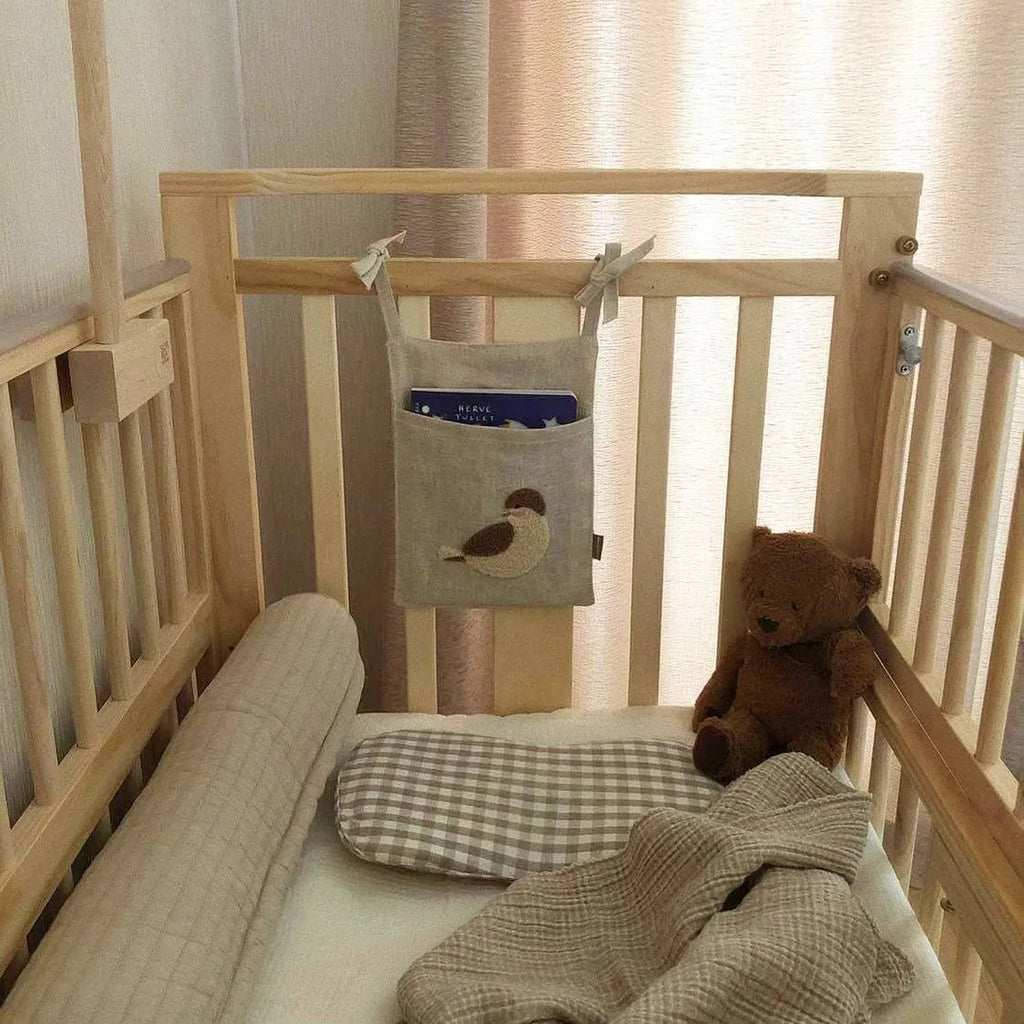 Khaki cotton and linen multi-purpose storage bag hanging beside the bed with single pocket