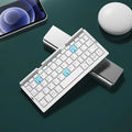 Silver white folding Bluetooth keyboard open with phone on stand and closed showing compact size