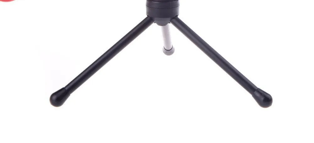 Black wired PC microphone with separate metal clip holder on a desk next to a computer.