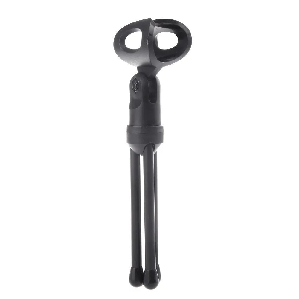 Black wired PC microphone with separate metal clip holder on a desk next to a computer.