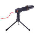Black wired PC microphone with separate metal clip holder on a desk next to a computer.