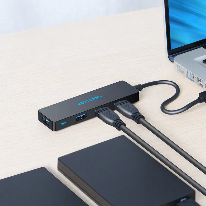 Black four-port USB 3.0 hub with a short connected cable on a white background