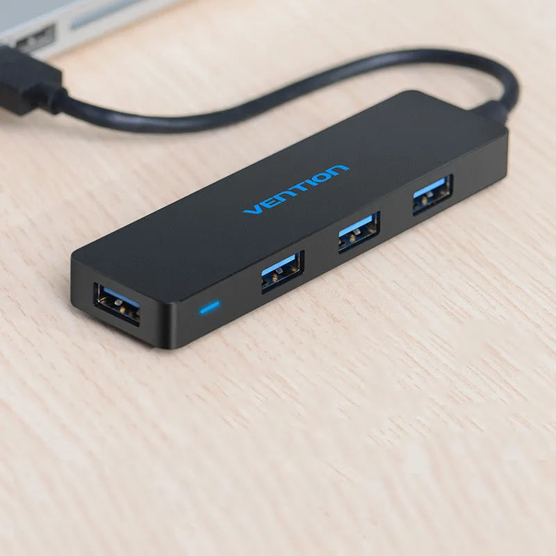 Black four-port USB 3.0 hub with a short connected cable on a white background