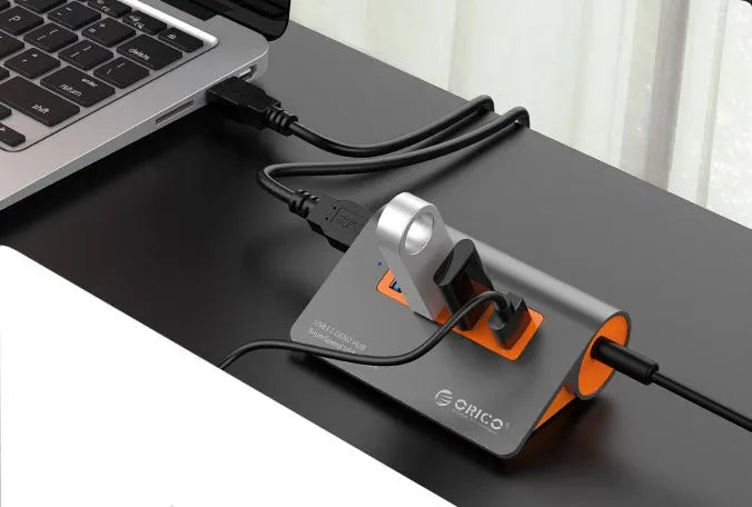 Dark grey aluminium alloy USB 3.1 laptop hub with four ports, orange accents, and detachable cable
