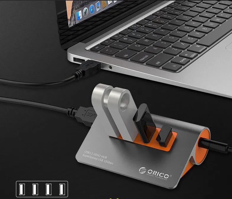 Dark grey aluminium alloy USB 3.1 laptop hub with four ports, orange accents, and detachable cable