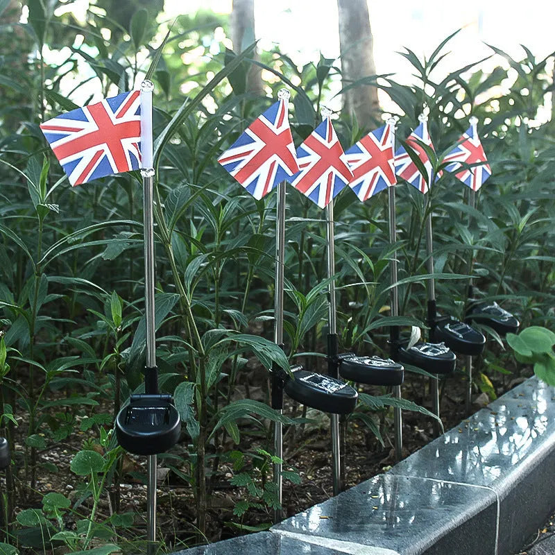 Solar-powered garden flag light displaying either American or British flag design with stainless steel pole and solar panel