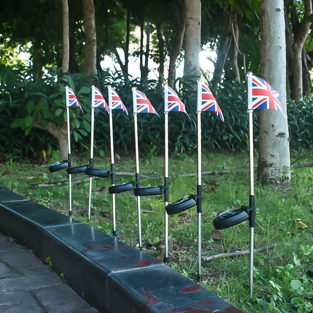 Solar-powered garden flag light displaying either American or British flag design with stainless steel pole and solar panel