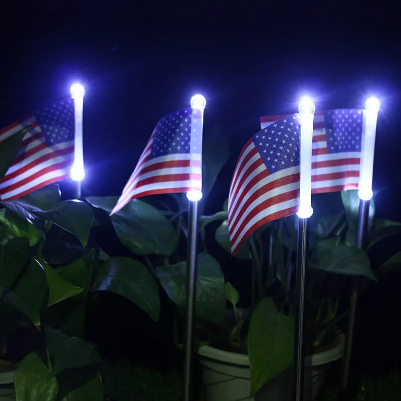 Solar-powered garden flag light displaying either American or British flag design with stainless steel pole and solar panel