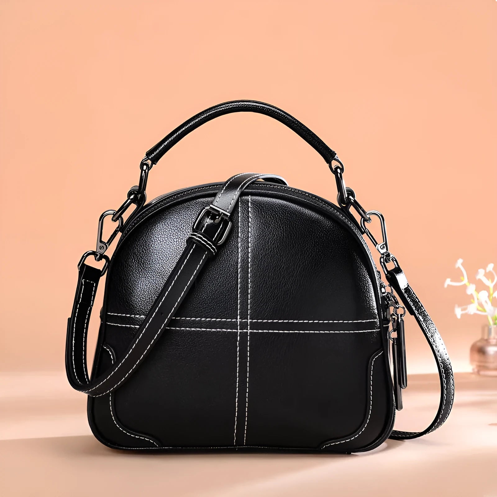 Round leather women's handbag with double soft handles and zipper closure in wine red colour