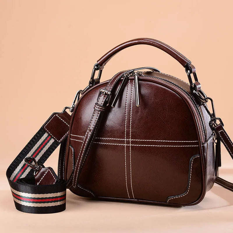 Round leather women's handbag with double soft handles and zipper closure in wine red colour