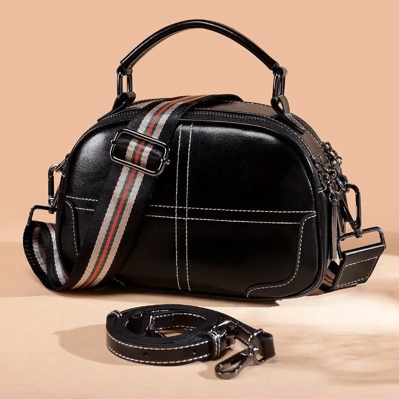 Round leather women's handbag with double soft handles and zipper closure in wine red colour